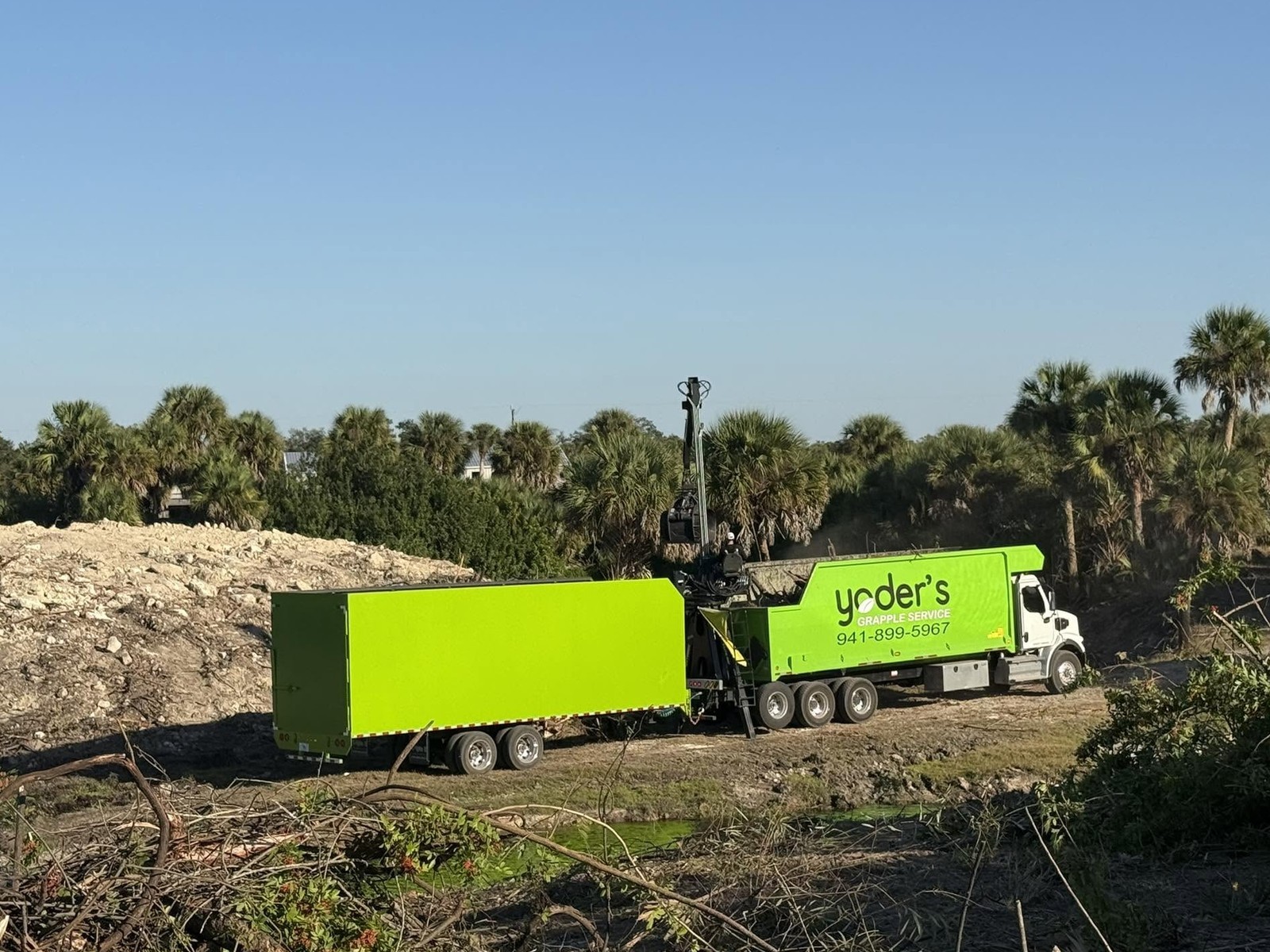 Grapple truck and trailer clearing a lot in Sarasota FL