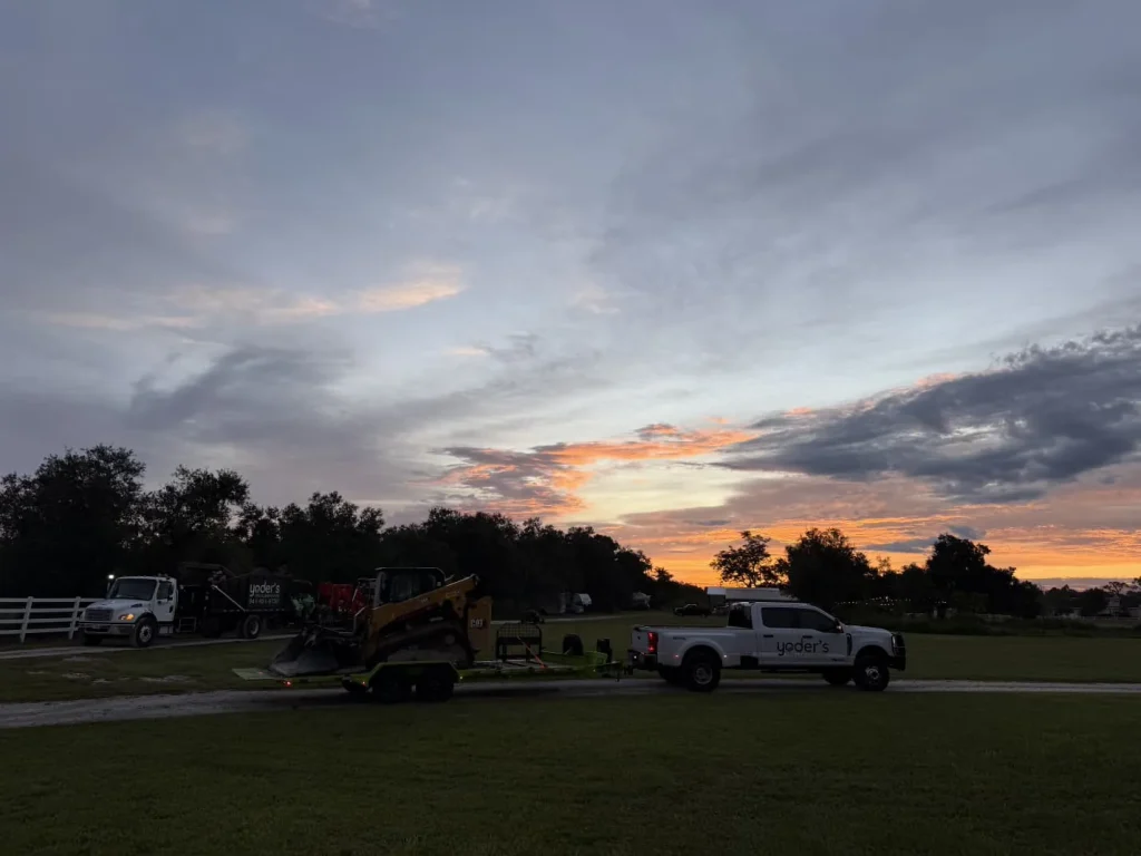 Yoder's Tree & Land Services trucks and equipment at sunset in Sarasota, FL